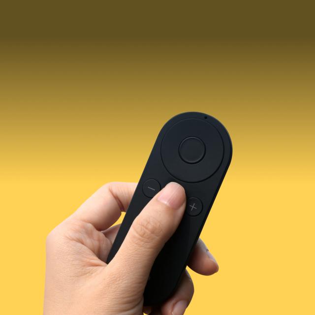 Lightweight remote control for Pivo Pods, held in hand, against yellow background.